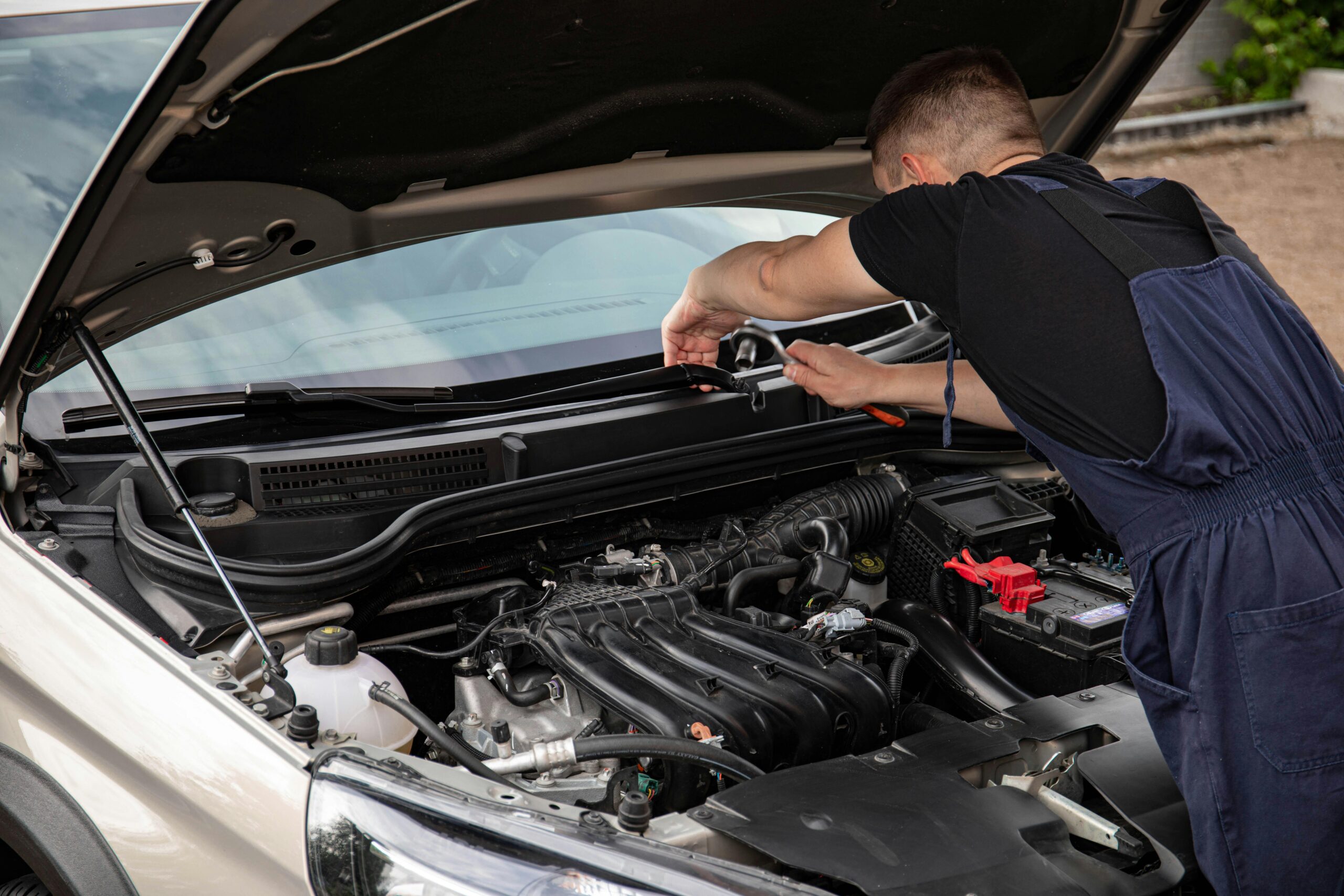 Une personne regarde l'intérieur du moteur d'une voiture.