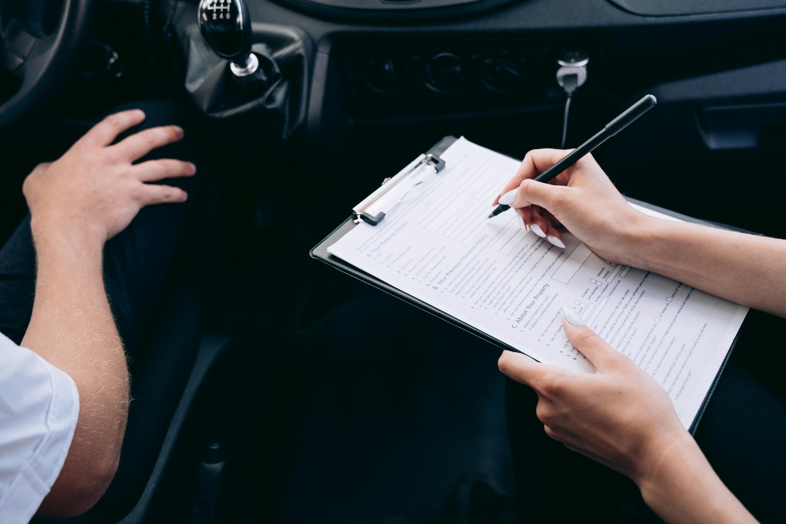 Une personne remplissant un document de type contrat dans une voiture